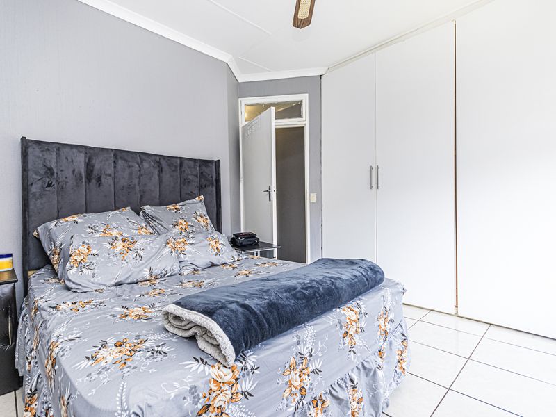 A bedroom featuring tiled flooring, a ceiling fan, and ample built-in cupboard storage space.