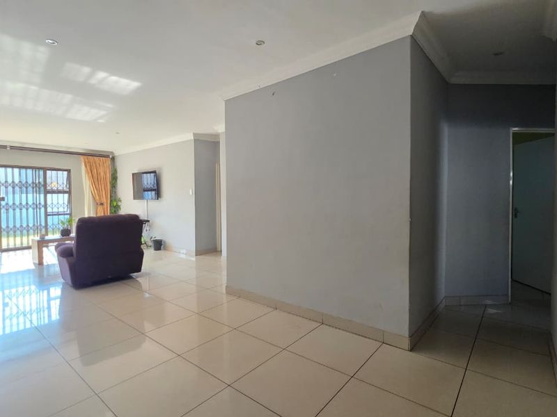 Spacious open-plan living area featuring neutral tiled flooring, recessed lighting, and a large sliding glass door providing access to the exterior.