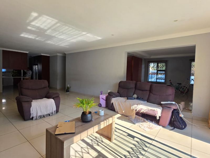 Spacious open-plan living area featuring neutral tiled flooring, recessed lighting, and a seamless flow into the adjacent kitchen space.