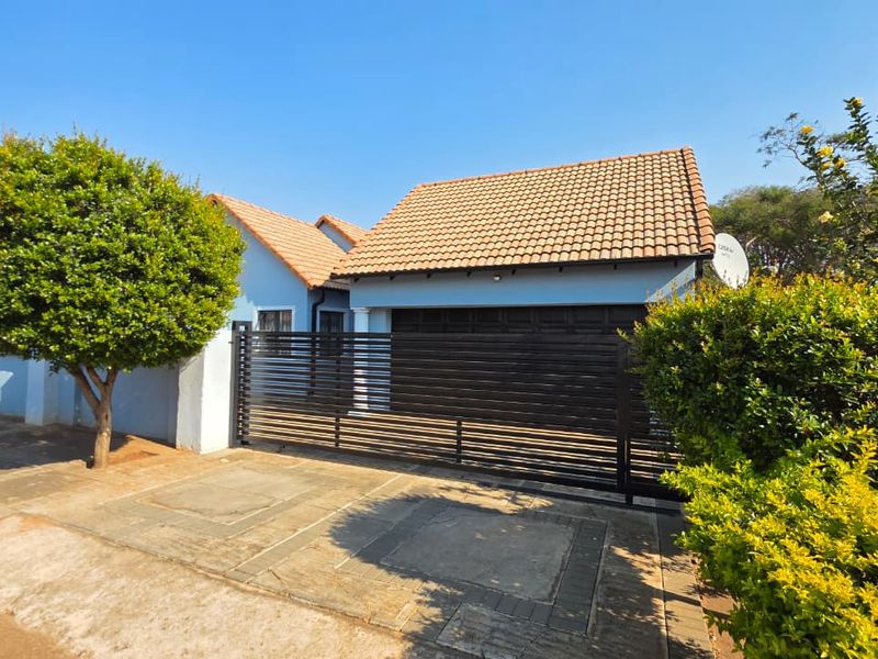 Front exterior view of the house featuring a tiled roof, a modern horizontal slat gate, and a paved driveway.