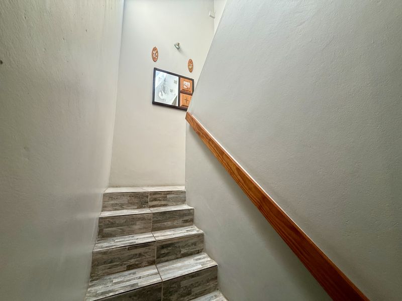 A staircase featuring tiled treads and a wooden handrail, providing access between levels within the townhouse.