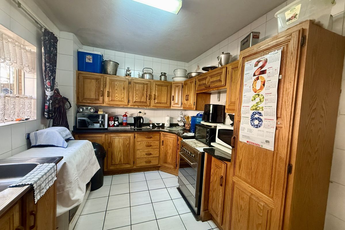 A functional kitchen featuring traditional wooden cabinetry, tiled flooring, and a tiled backsplash, offering a classic layout with ample storage space.