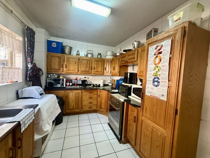A functional kitchen featuring traditional wooden cabinetry, tiled flooring, and a tiled backsplash, offering a classic layout with ample storage space.