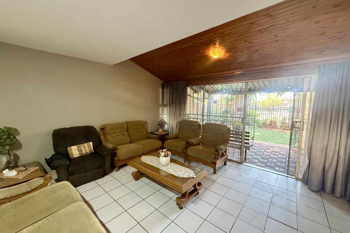 Spacious living room featuring tiled flooring and a warm timber-clad vaulted ceiling, with direct access to the rear patio through sliding glass doors.