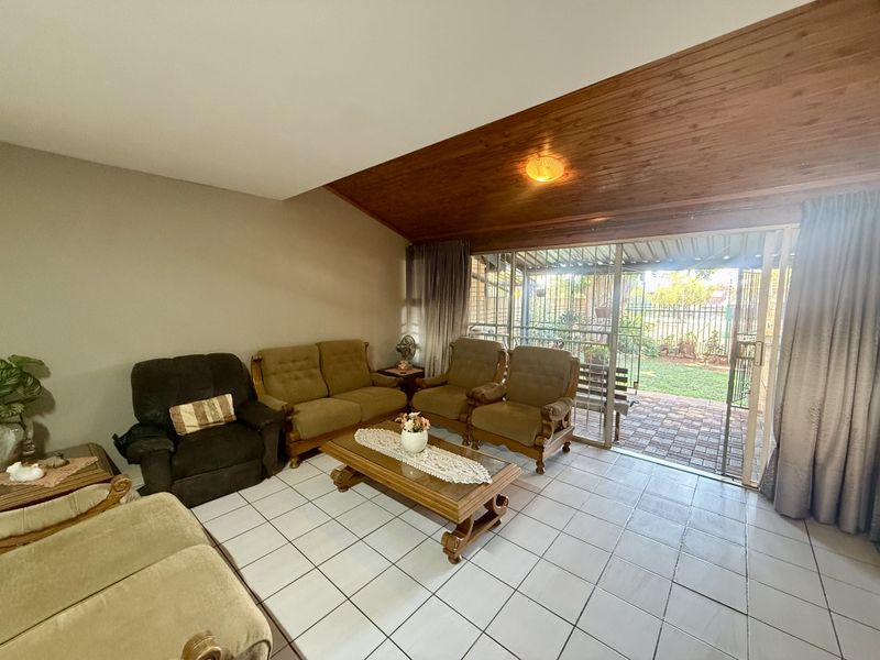 Spacious living room featuring tiled flooring and a warm timber-clad vaulted ceiling, with direct access to the rear patio through sliding glass doors.