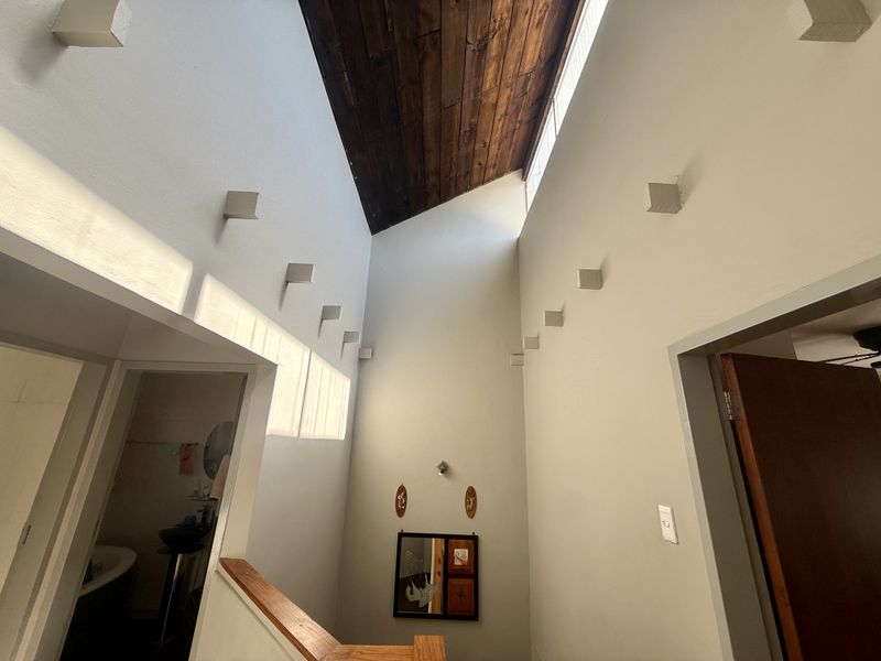 A bright hallway featuring a high vaulted timber ceiling, clerestory windows, and a skylight, creating an airy and architectural transition space.