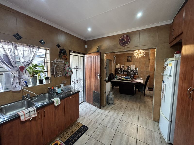 Functional kitchen featuring wooden cabinetry, granite countertops, and double stainless steel sink, with direct access to the adjacent dining area.