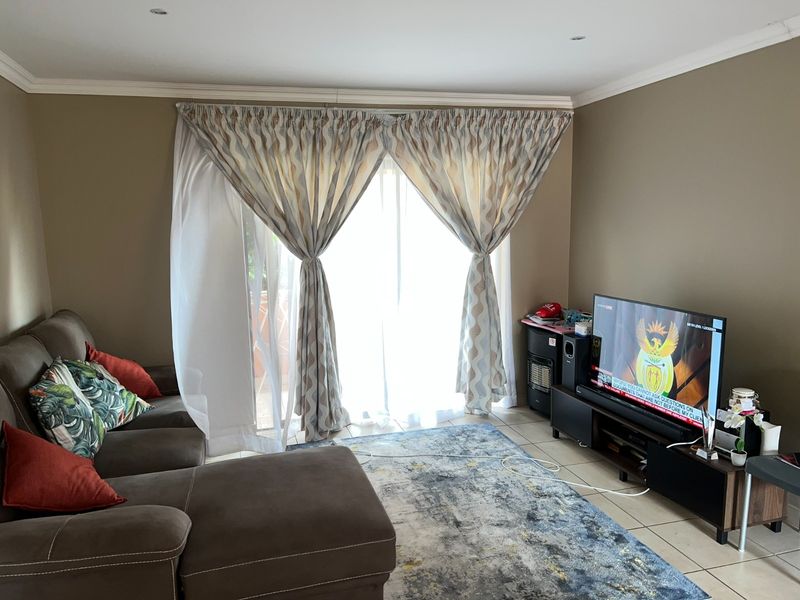 A comfortable living room featuring tiled flooring, recessed lighting, and a sliding glass door that provides access to the outdoor area.