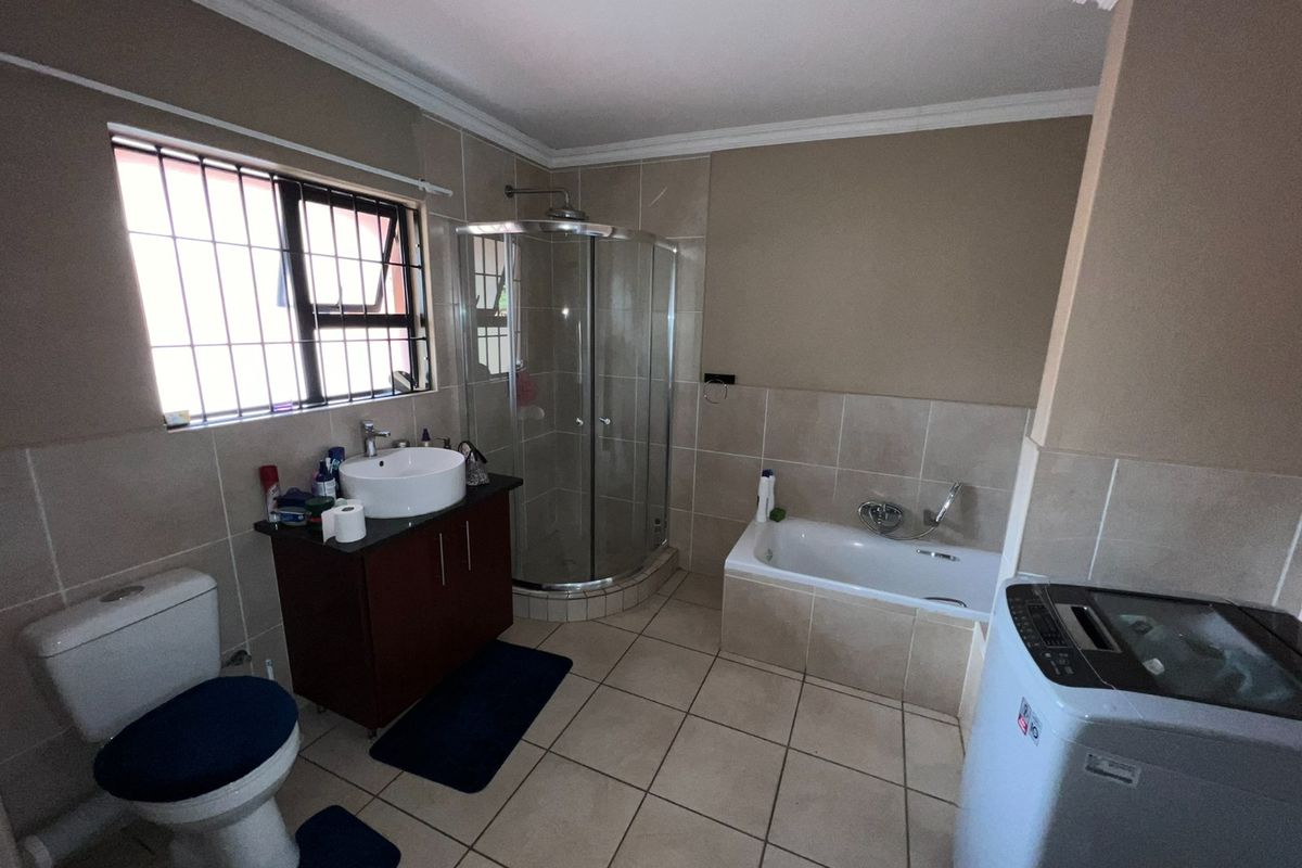 A functional bathroom featuring a separate shower enclosure, bathtub, vanity with vessel sink, and tiled finishes throughout.