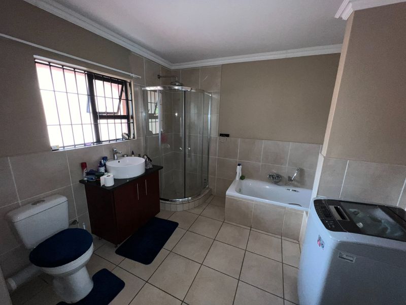A functional bathroom featuring a separate shower enclosure, bathtub, vanity with vessel sink, and tiled finishes throughout.