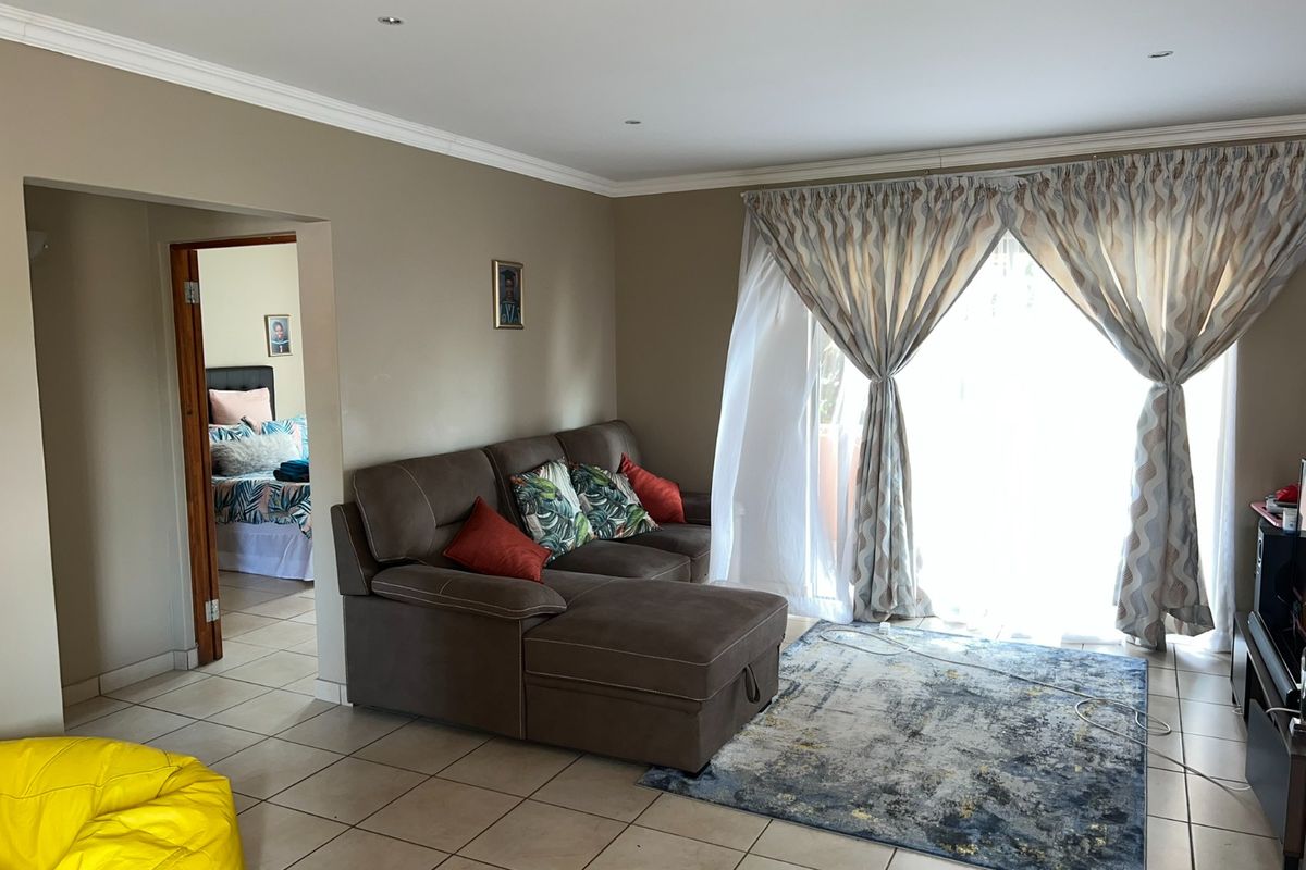 A living room featuring tiled flooring, recessed downlighting, and a sliding glass door providing access to the exterior.