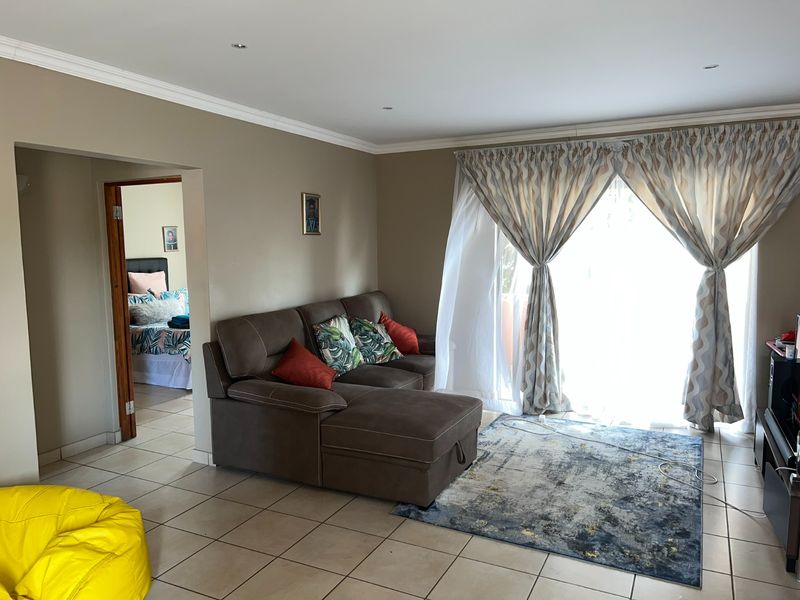 A living room featuring tiled flooring, recessed downlighting, and a sliding glass door providing access to the exterior.