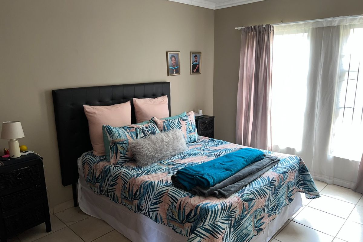 A well-lit bedroom featuring tiled flooring, neutral wall tones, and a sliding door providing access to natural light.