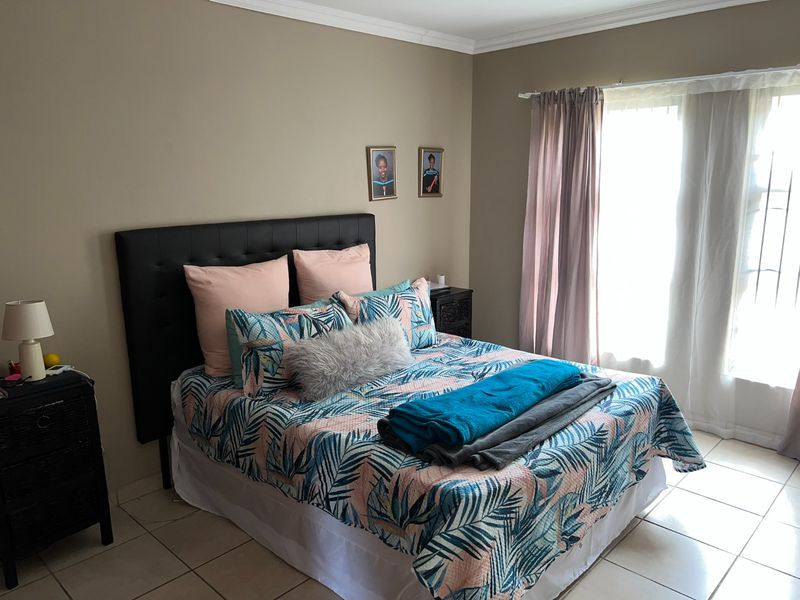 A well-lit bedroom featuring tiled flooring, neutral wall tones, and a sliding door providing access to natural light.