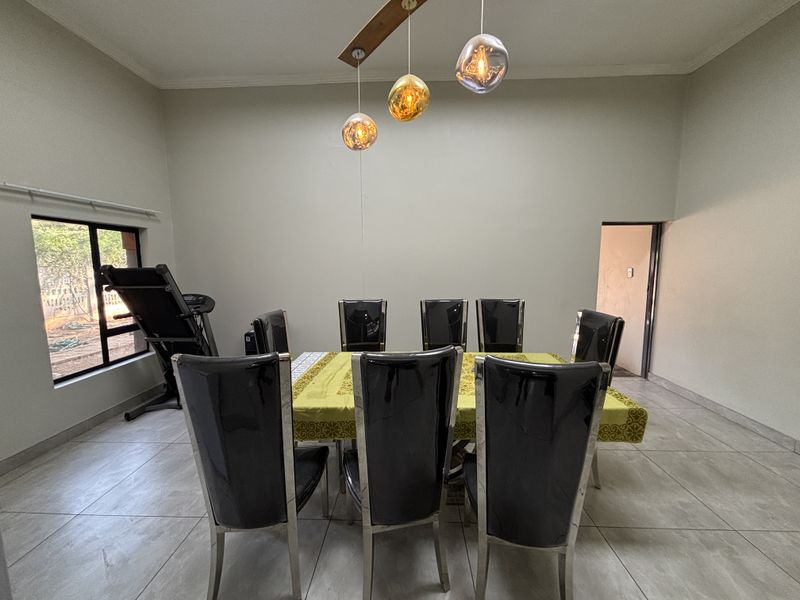 A spacious dining room featuring neutral walls, large tiled flooring, and modern pendant lighting, providing a clean and functional space for family meals.