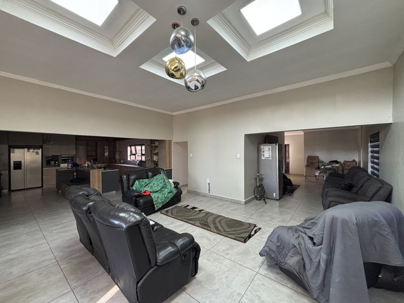Spacious open-plan living area featuring a kitchen with built-in cabinetry, tiled floors, and a distinctive recessed ceiling with skylights.