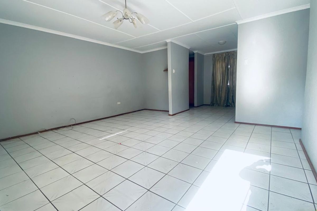 An empty, open-plan living area featuring neutral wall paint and tiled flooring, offering a blank canvas for interior design.