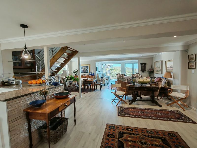 Spacious open-plan living and kitchen area featuring light laminate flooring, a timber staircase with stainless steel balustrades, and large sliding doors leading to a balcony.