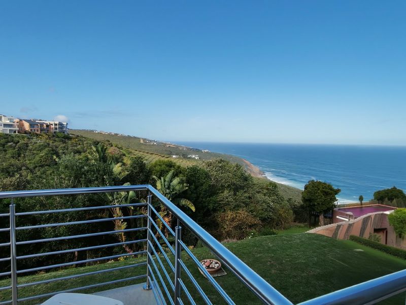 Elevated coastal view overlooking the ocean and surrounding landscape, featuring a modern stainless steel balustrade.