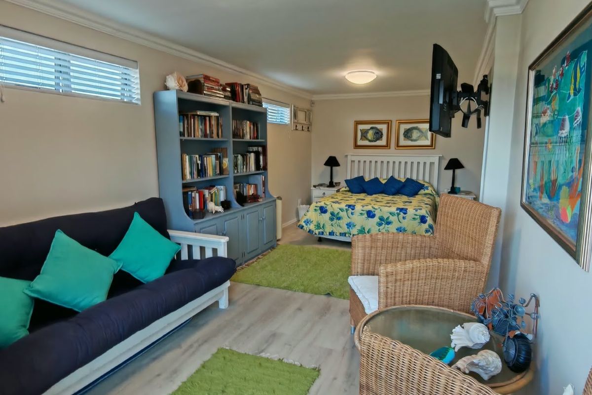 A spacious bedroom featuring light-toned laminate flooring, crown molding, and a wall-mounted television bracket, offering a comfortable and functional living space.
