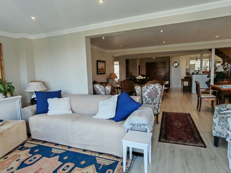 Spacious open-plan living area featuring laminate flooring, recessed downlighting, and crown molding, creating a connected flow between the lounge and dining spaces.