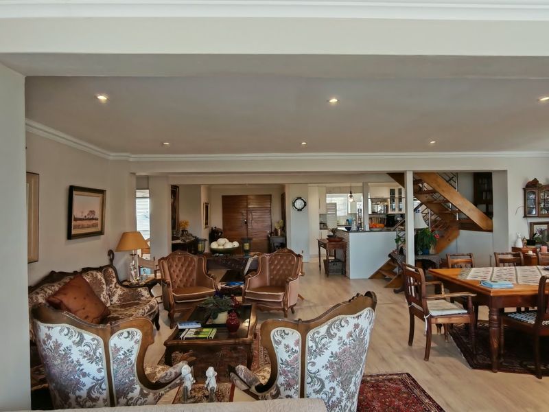 Spacious open-plan living and dining area featuring laminate flooring, recessed lighting, and a timber staircase leading to the upper level.