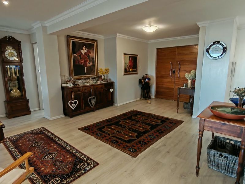 Spacious entrance hall featuring light-toned laminate flooring, decorative cove cornicing, and impressive double timber doors.