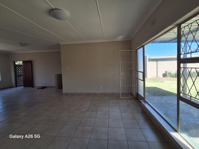 A spacious, empty living area featuring neutral tiled flooring, large sliding glass doors providing natural light, and direct access to the outdoor patio.