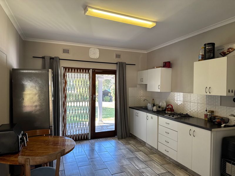 Functional kitchen featuring white cabinetry, gas hob, tiled splashback, and direct access to the rear garden through a sliding glass door.