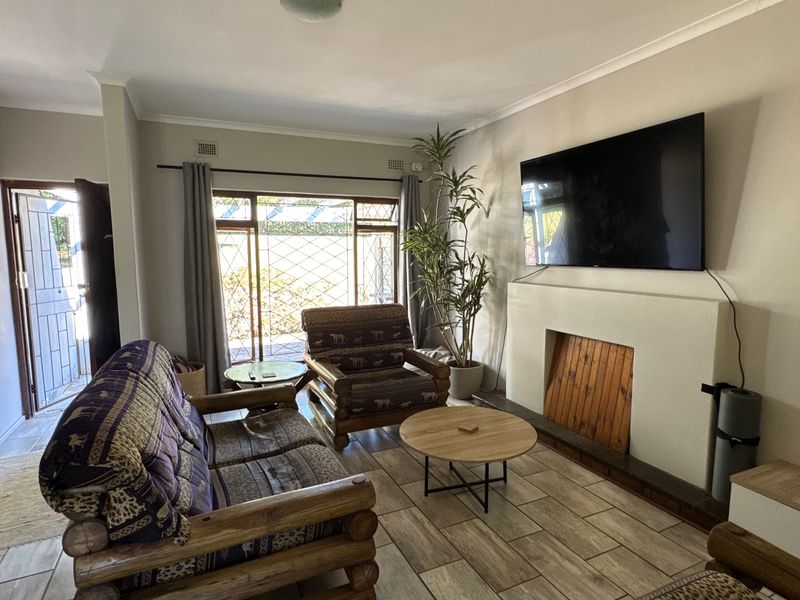 A comfortable living room featuring tiled flooring, a built-in fireplace, and a sliding glass door providing access to the exterior.