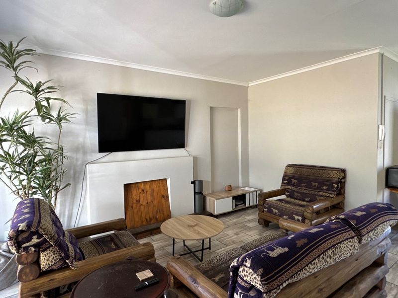 A living room featuring a built-in fireplace, tiled flooring, and coved ceilings, providing a functional and neutral space for relaxation.