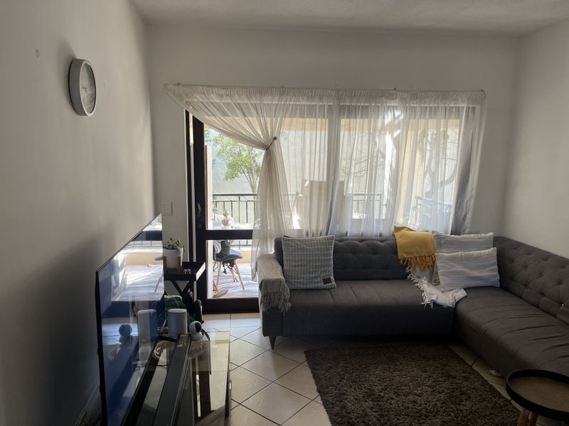 A comfortable living room featuring tiled flooring and a large sliding glass door that provides direct access to an outdoor balcony area.
