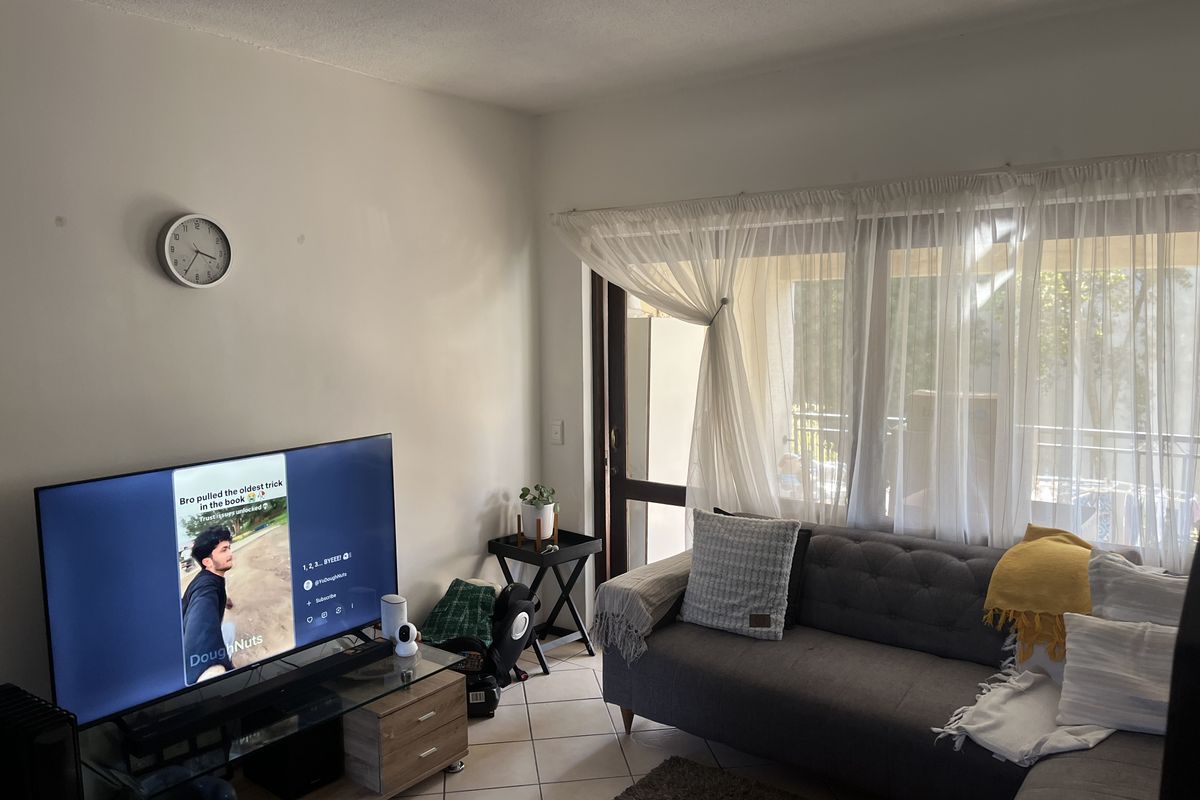 A comfortable living room featuring tiled flooring and a large sliding glass door that provides access to the outdoor area.