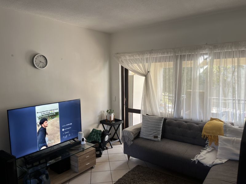 A comfortable living room featuring tiled flooring and a large sliding glass door that provides access to the outdoor area.