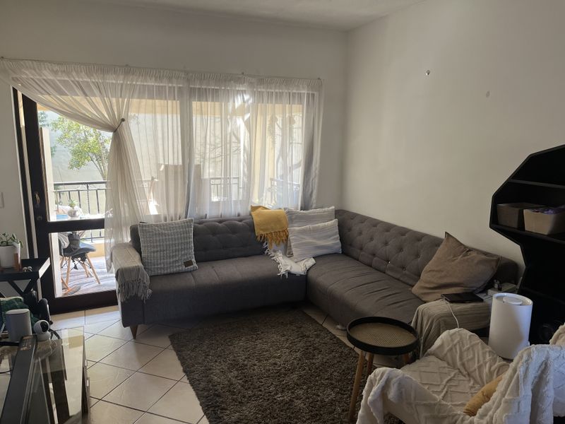 A living room featuring ceramic floor tiles and a large sliding glass door providing access to an outdoor balcony area.