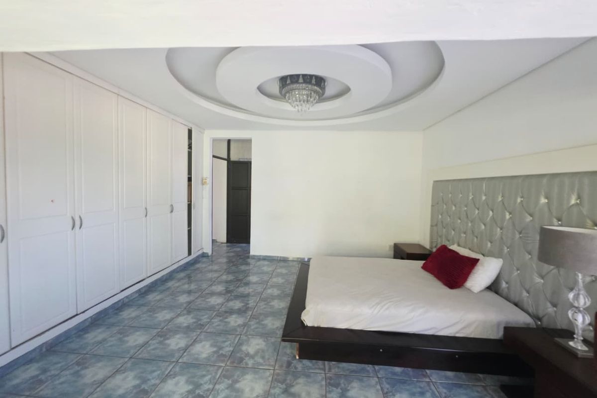 Spacious bedroom featuring built-in wardrobes, a decorative recessed ceiling design, and tiled flooring.