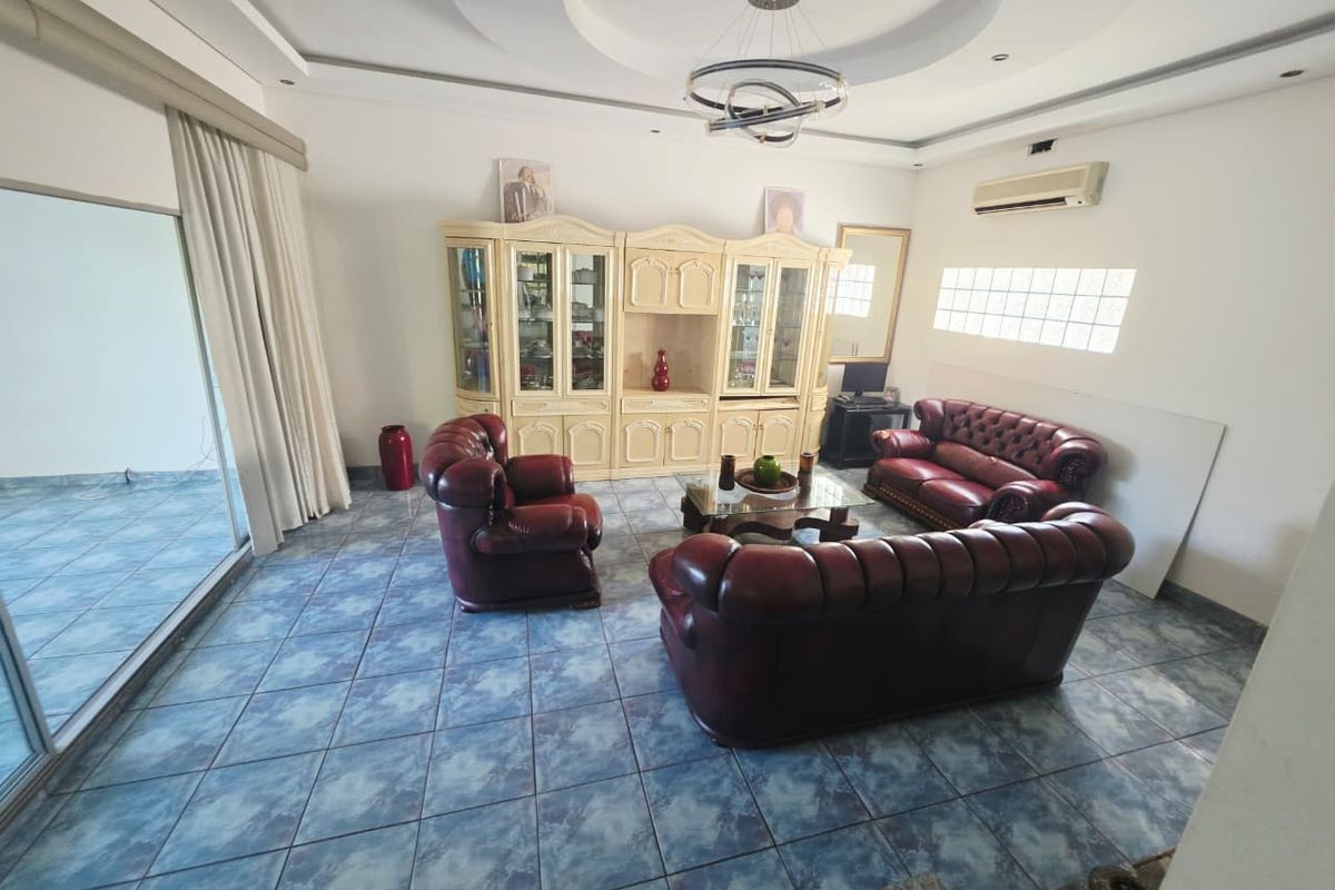 Spacious living room featuring tiled flooring, a recessed ceiling with modern lighting, a split-system air conditioner, and large sliding glass doors leading outdoors.