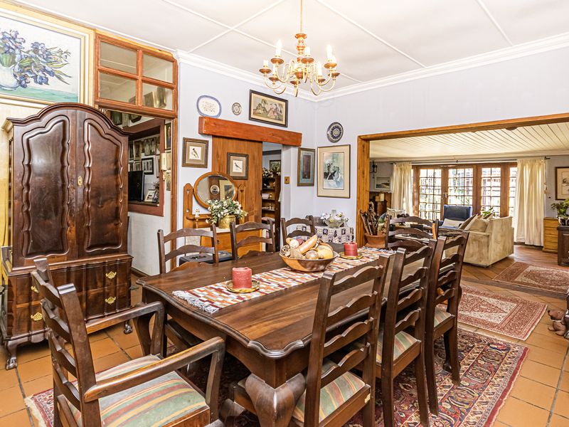 Spacious open-plan dining and living area featuring traditional terracotta tile flooring, exposed timber ceiling beams, and a classic sliding timber barn door.
