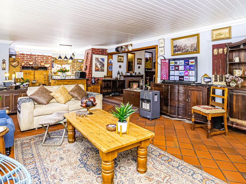 Spacious open-plan living area featuring terracotta tile flooring, a tongue and groove ceiling, and an exposed brick fireplace.