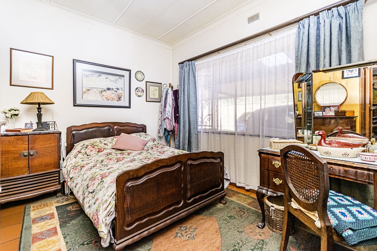 A bedroom featuring classic architectural details including a traditional cornice and ceiling air vent, offering a functional space with natural light.