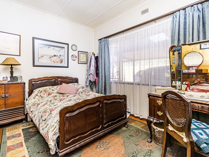 A bedroom featuring classic architectural details including a traditional cornice and ceiling air vent, offering a functional space with natural light.