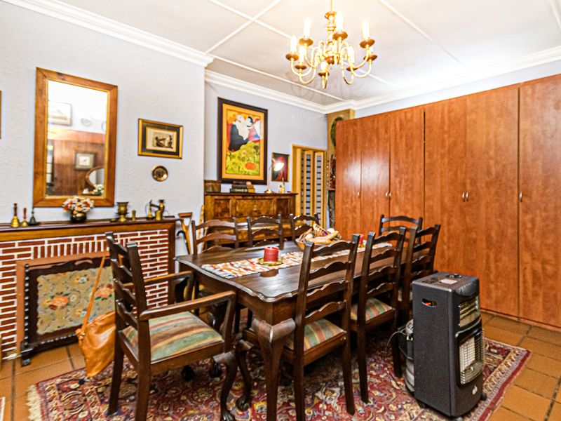 A traditional dining room featuring built-in wooden cabinetry, a brick fireplace surround, tiled flooring, and decorative ceiling coving.