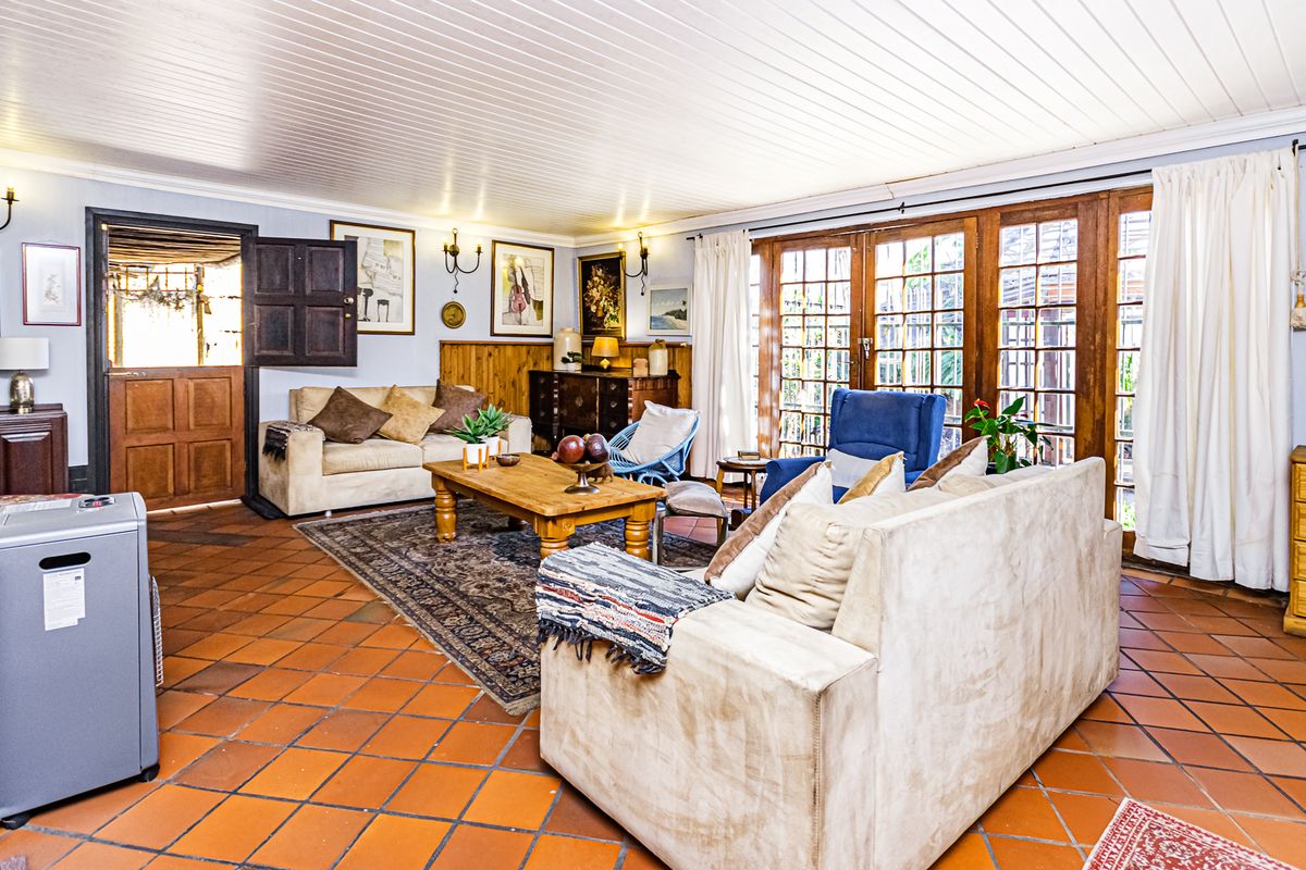 Spacious living room featuring terracotta floor tiles, timber panelled ceilings, and large timber-framed glass doors providing access to the outdoor area.