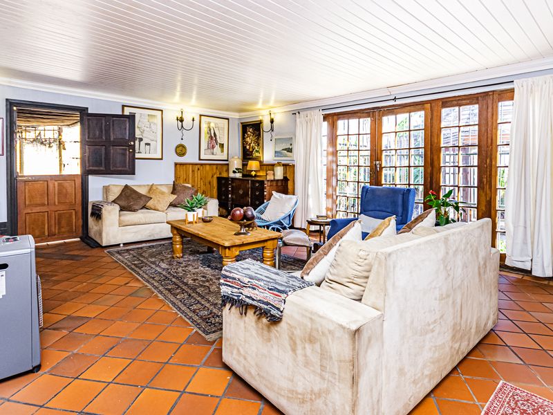 Spacious living room featuring terracotta floor tiles, timber panelled ceilings, and large timber-framed glass doors providing access to the outdoor area.