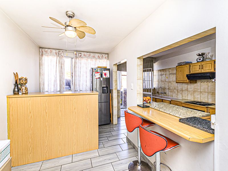 Open plan kitchen and dining area featuring a granite breakfast bar, tiled flooring, and functional built-in cabinetry with integrated appliances.