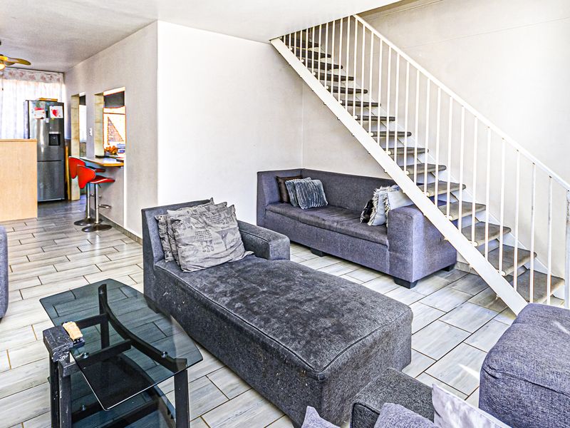 Open plan living area featuring tiled flooring, a breakfast bar, and a staircase leading to the upper level.