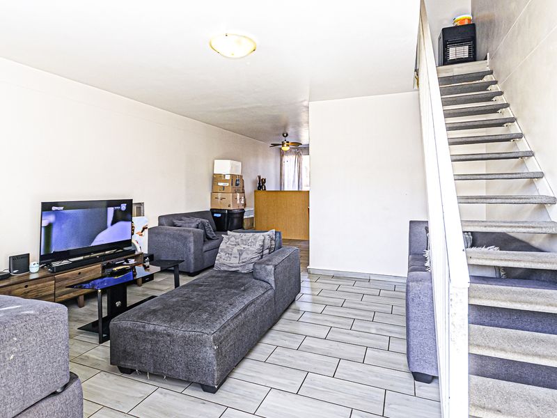 Open-plan living area featuring tiled flooring and a staircase leading to the upper level.
