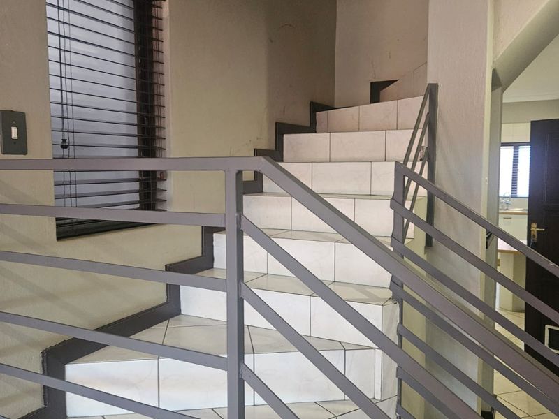 A functional staircase area featuring tiled steps and a metal balustrade, providing access between levels in the townhouse.