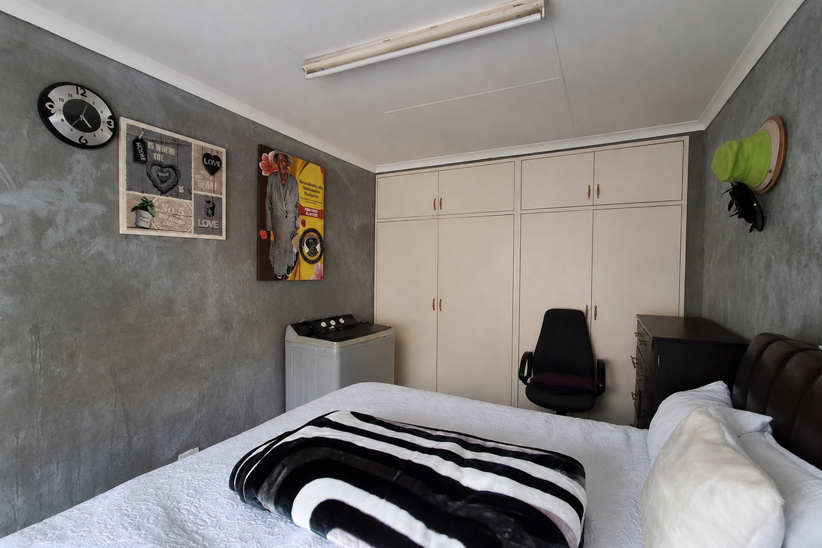 A bedroom featuring built-in cupboards and grey textured feature walls, providing functional storage space.