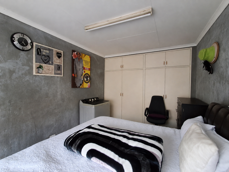 A bedroom featuring built-in cupboards and grey textured feature walls, providing functional storage space.